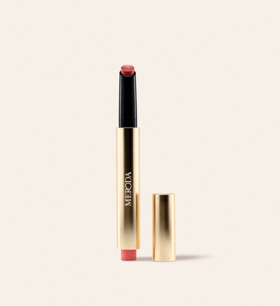 Hydrating Lip Tint in Peachy Rose in een slanke gouden metallic pen met losse dop op een crème achtergrond.