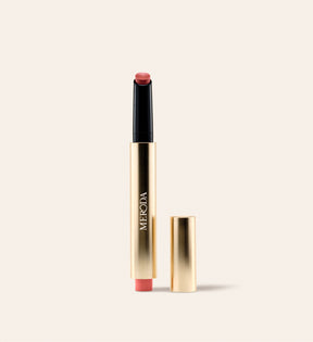Hydrating Lip Tint in Peachy Rose in een slanke gouden metallic pen met losse dop op een crème achtergrond.