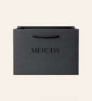 Matte zwarte Cadeautas met een geweven touwvatting en een in relief gedrukt Meroda logo op een creme achtergrond