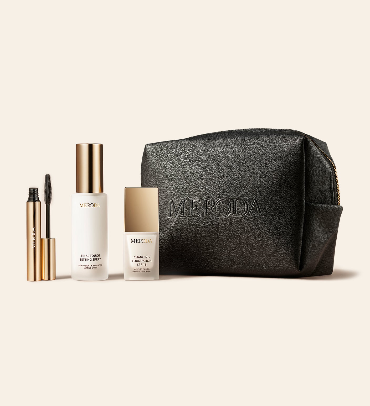 Travel Kit met Mini Gilded Lashes Mascara, Mini Final Touch Setting Spray, Mini Changing Foundation en zwarte reistas op een lichte achtergrond
