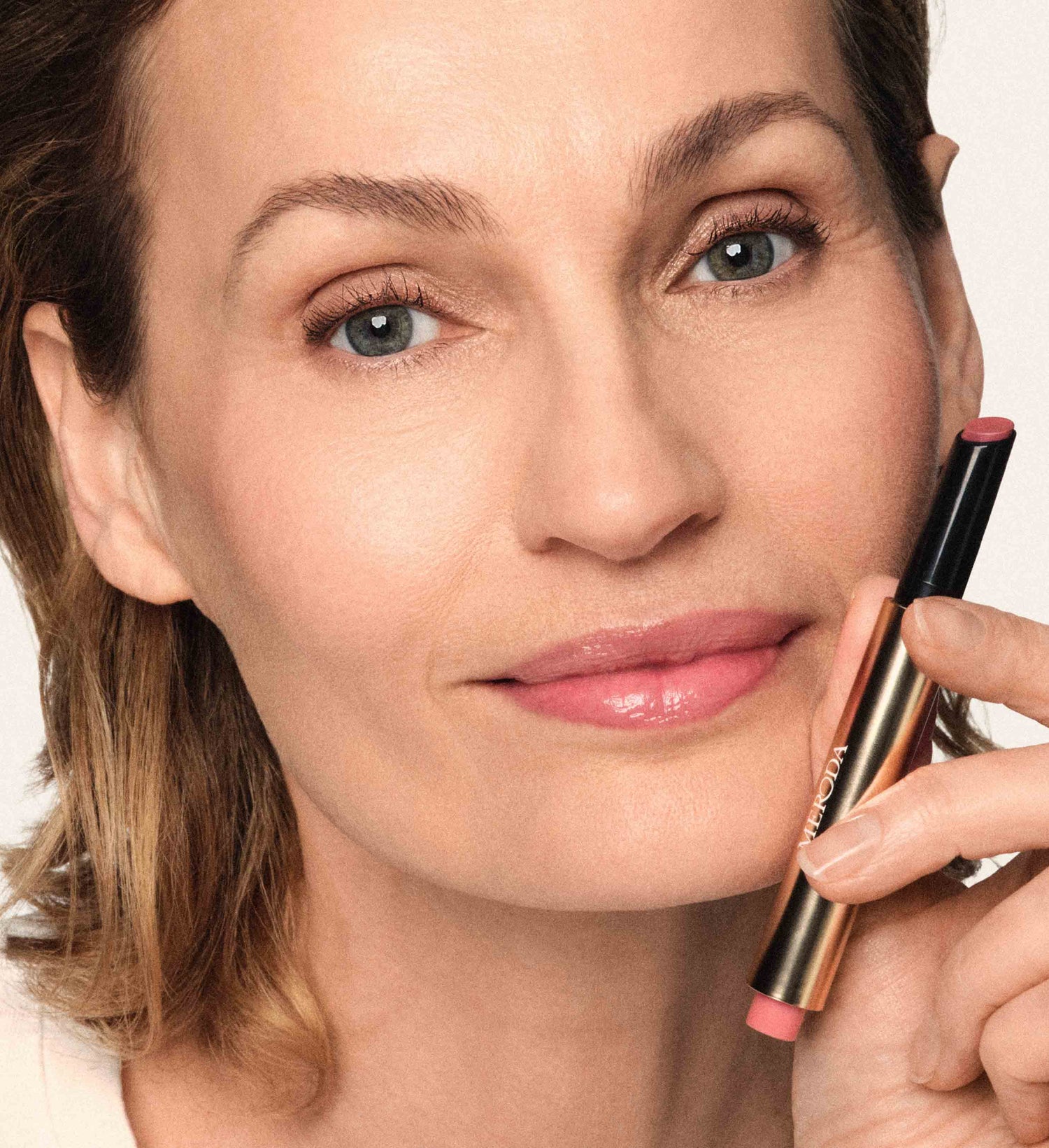 Hydrating Lip Tint in Dusty Rose vastgehouden door een model voor een natuurlijke, gezonde gloed.