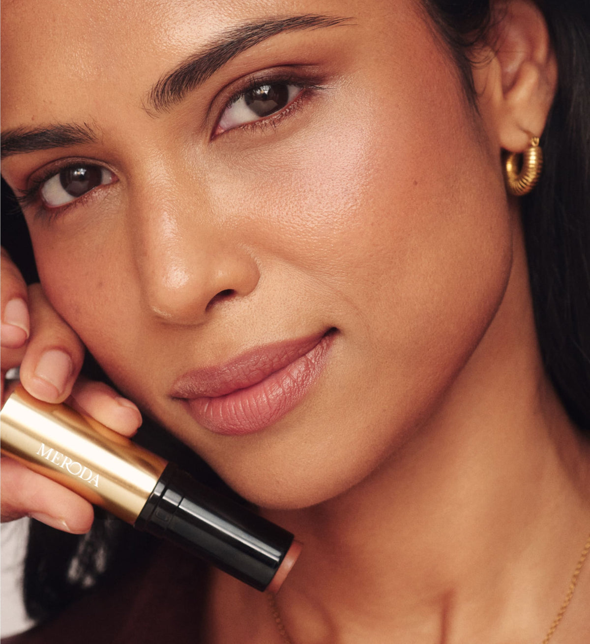 Soft Tan Bronzer in de tint Dark vastgehouden door een model voor een natuurlijke, zongebruinde en stralende finish