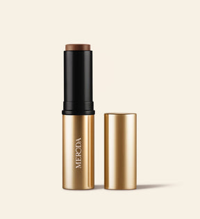 Soft Tan Bronzer in Deep, een romige stick in gouden verpakking met de bijpassende dop ernaast.