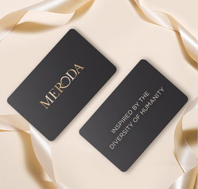 Meroda E-Gift Card met zwarte kaarten, gouden tekst en satijnen lint op een lichte achtergrond