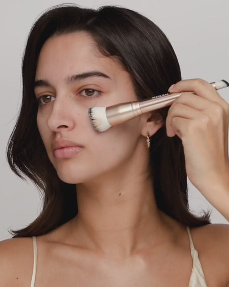 Vrouw brengt Changing Foundation aan met de 2-in-1 Build & Conceal Brush terwijl de kleur zich aanpast aan de huid.
